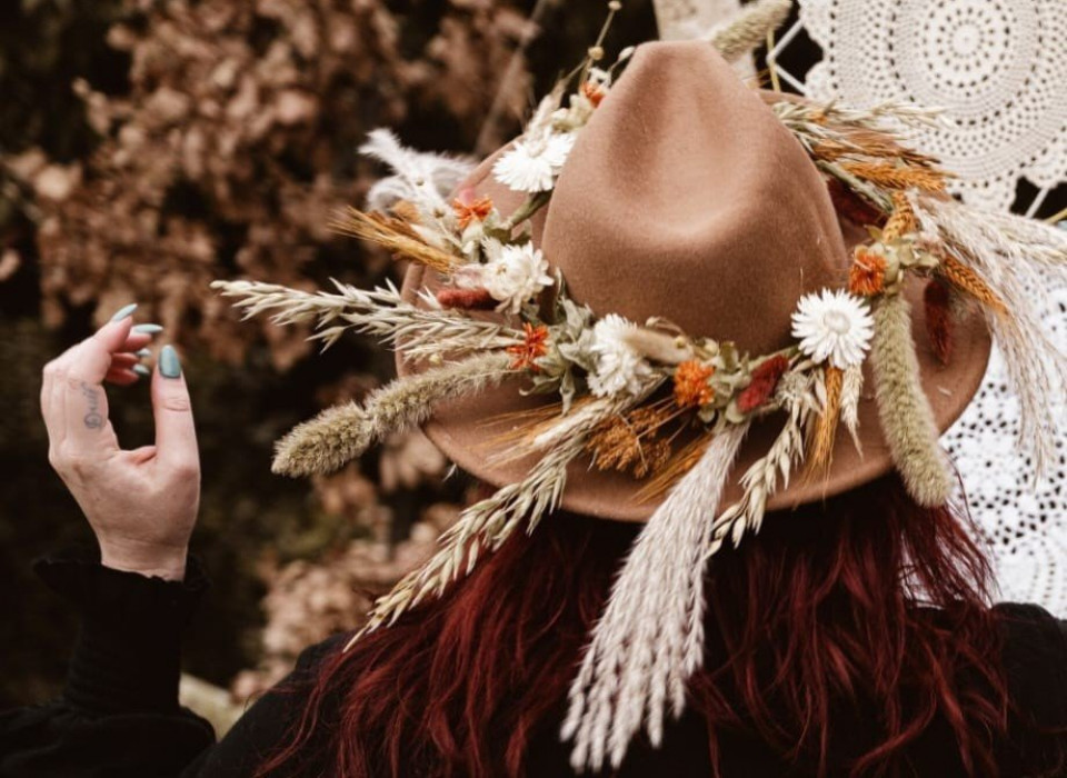 een vrouw met een hoed met bloemen en gedroogd gras
