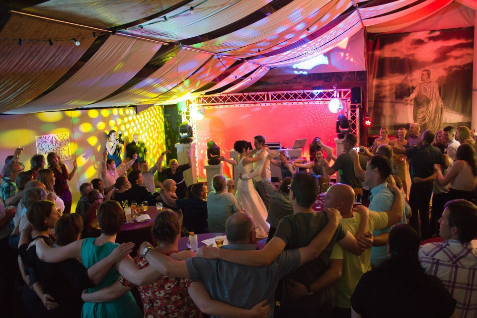 een grote groep mensen danst in een tent