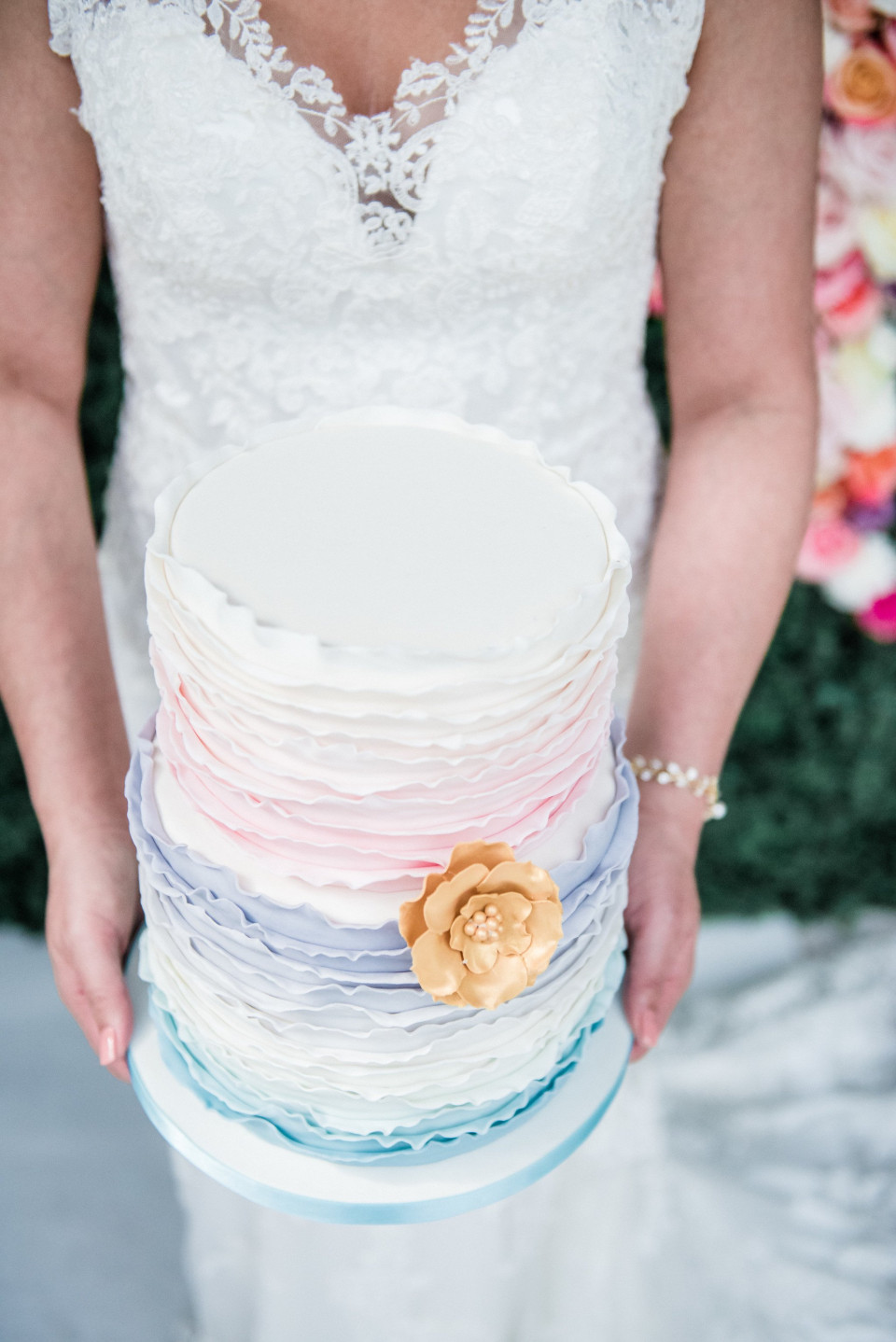 een bruid die een kleurrijke taart met bloemen vasthoudt