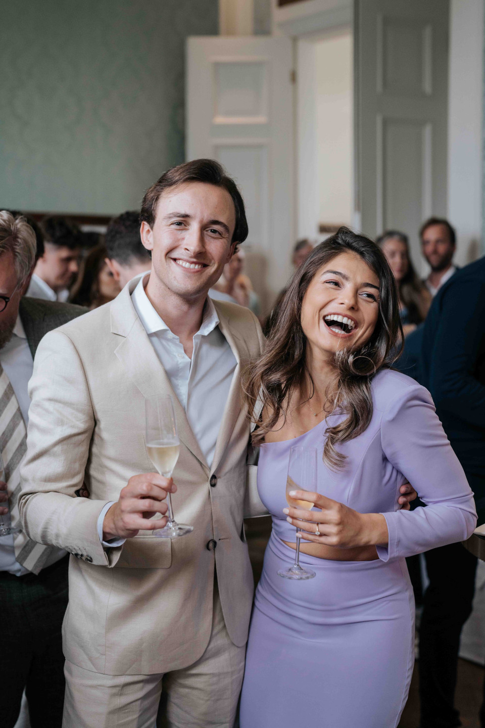 een stel in een wit pak en een vrouw in een paarse jurk