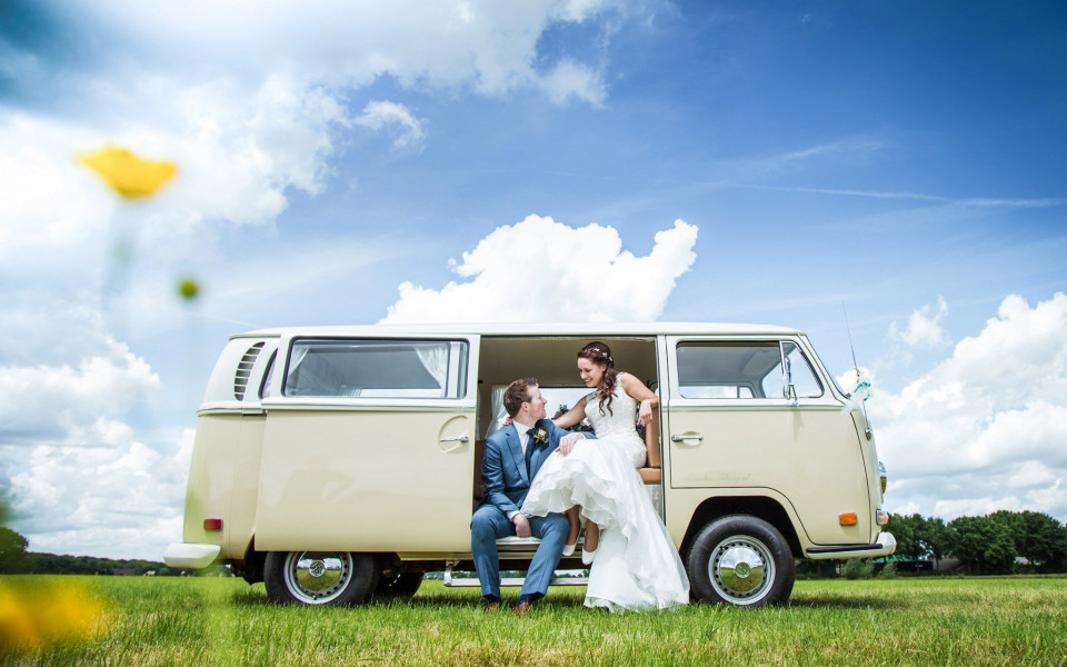 een bruid en bruidegom zitten voor een vw camperbus