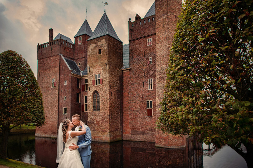 een bruid en bruidegom die voor een kasteel staan