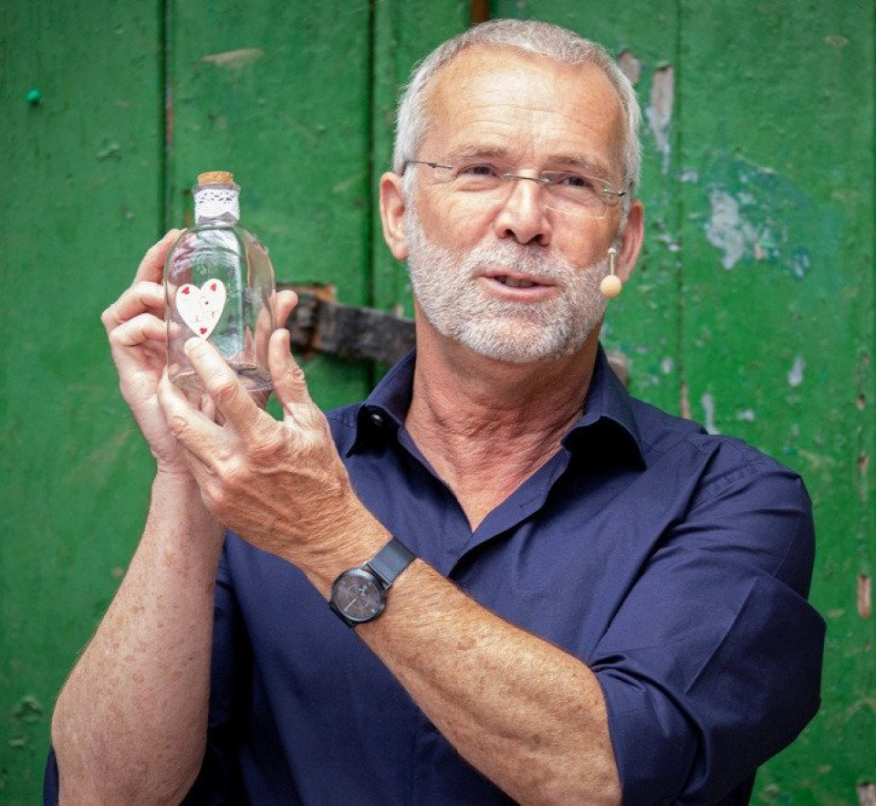 een man die een fles wodka vasthoudt voor een groene deur