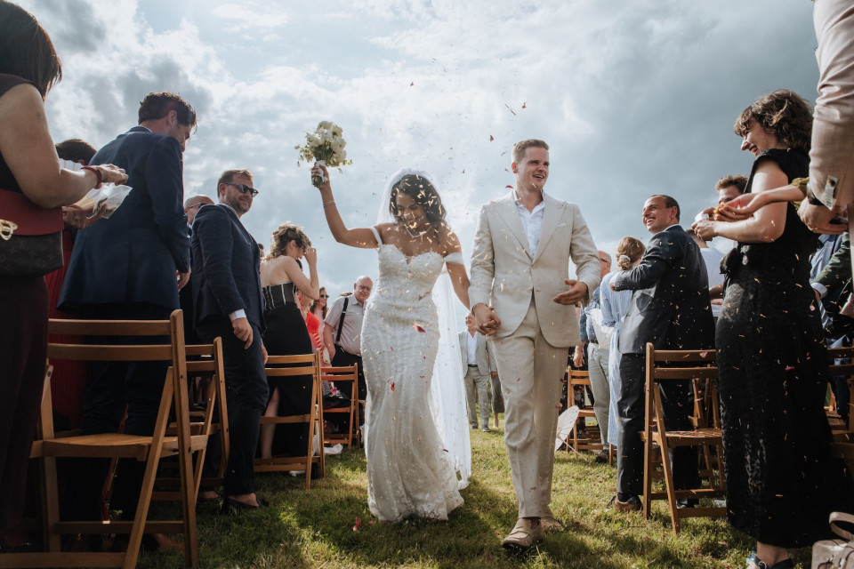 een bruid en bruidegom die door het gangpad lopen met confetti in de lucht terwijl ze de huwelijksceremonie verlaten