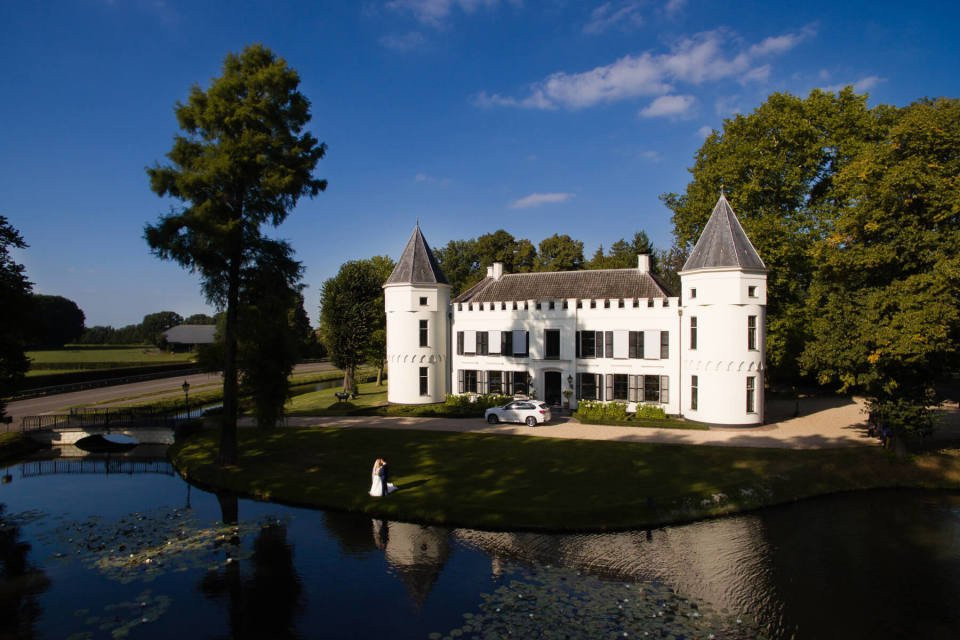 een groot wit kasteel met een vijver ervoor