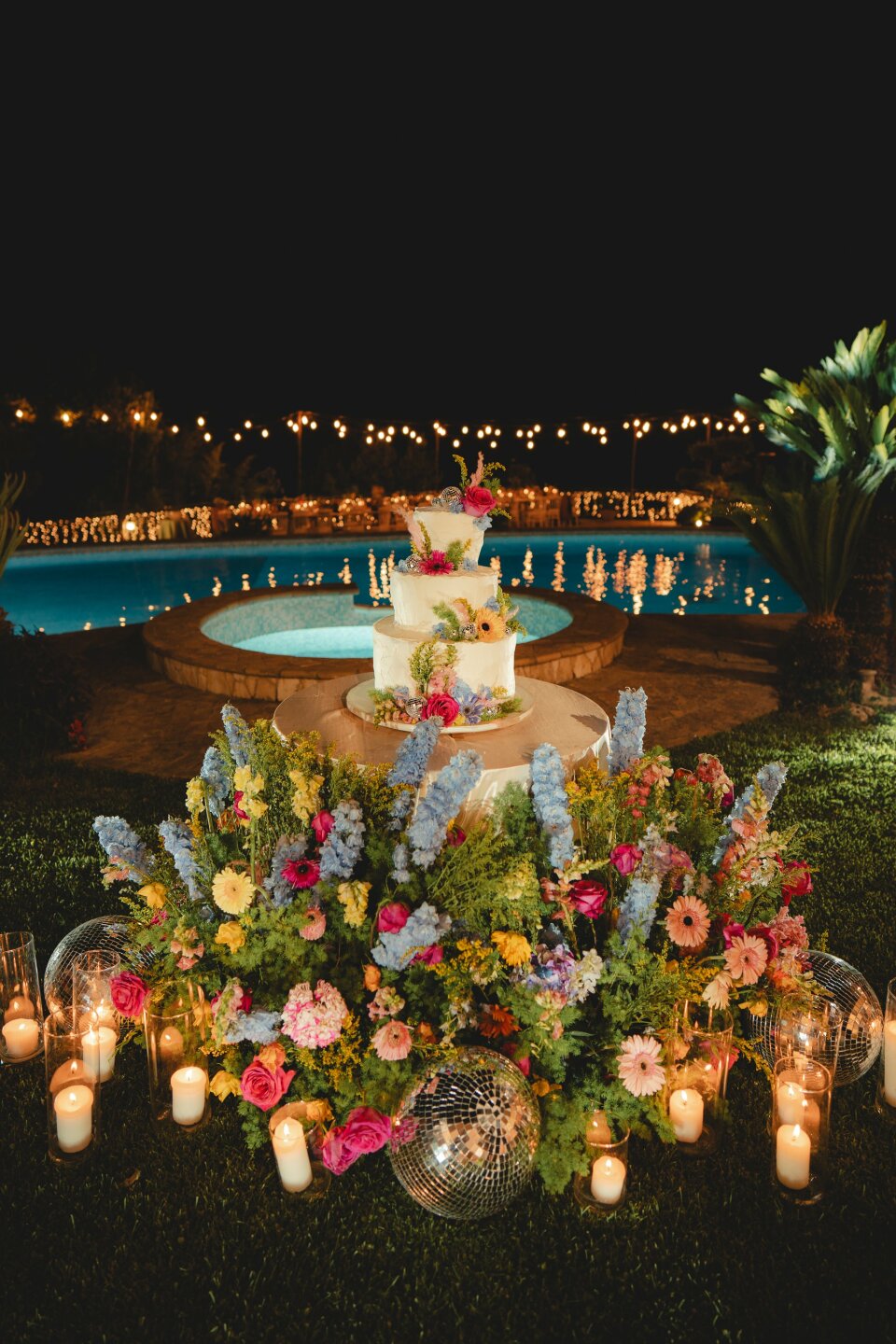een bruidstaart met bloemen en kaarsen voor een zwembad