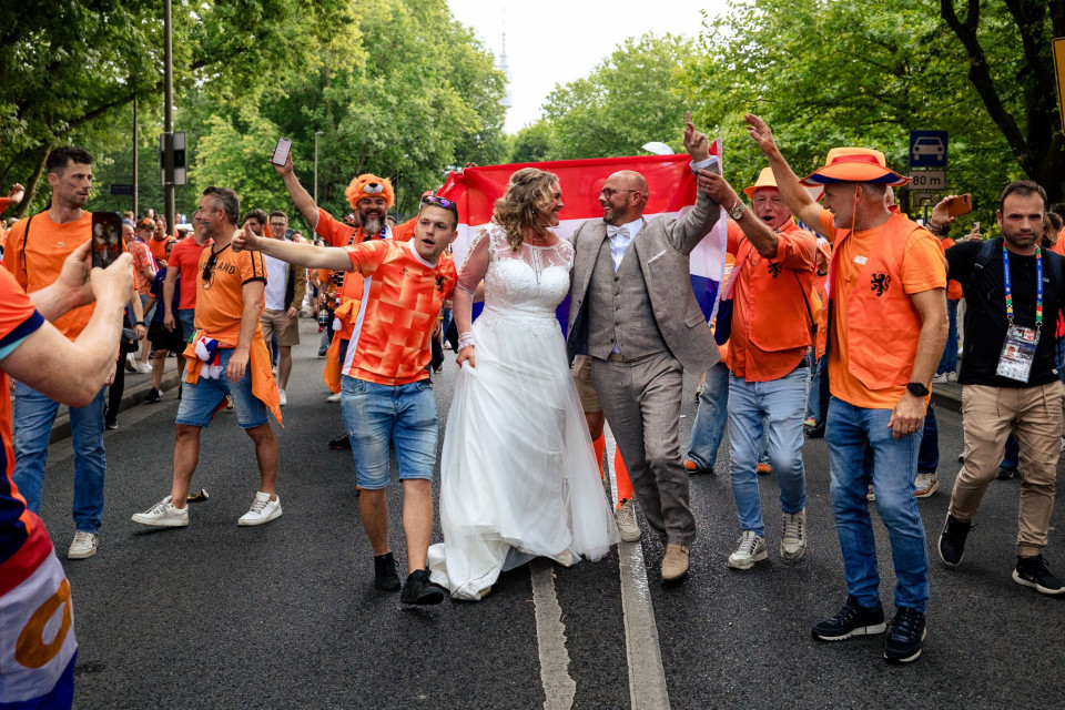 een bruid en bruidegom die de straat aflopen met andere mensen