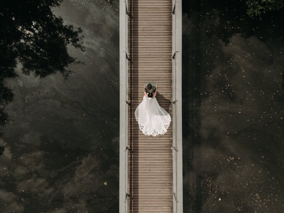 een vrouw in een trouwjurk die op een brug staat
