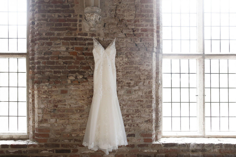 trouwjurk hangend in een oud bakstenen gebouw