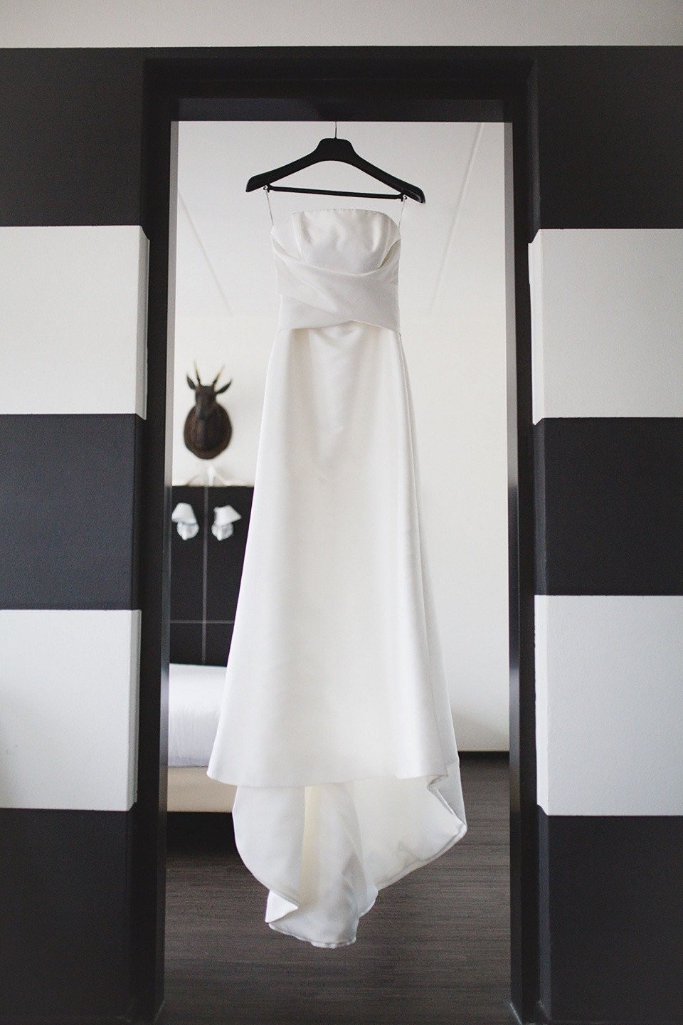 een trouwjurk hangend in een zwart-wit gestreepte kamer