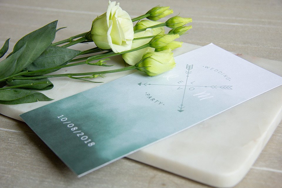 een witte en groene trouwuitnodiging met een boeket bloemen