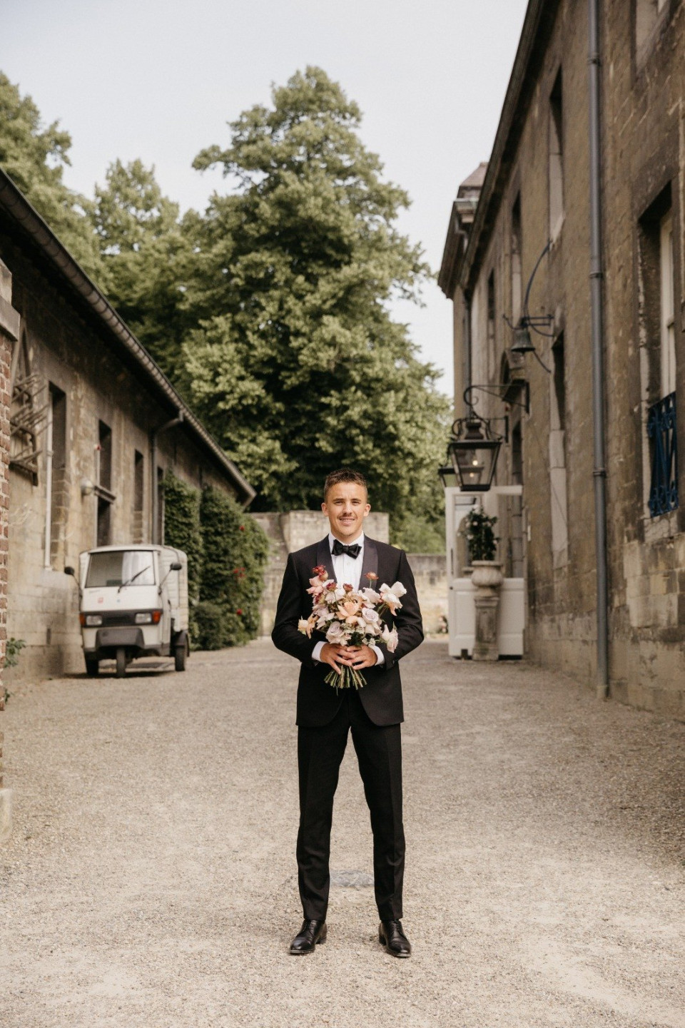een man in een smoking die een boeket bloemen vasthoudt