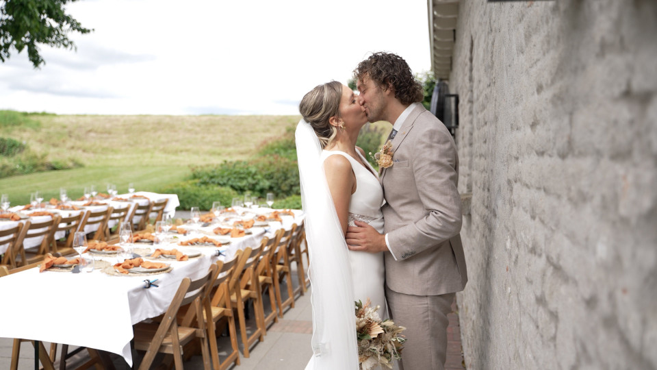 een bruid en bruidegom kussen voor een muur