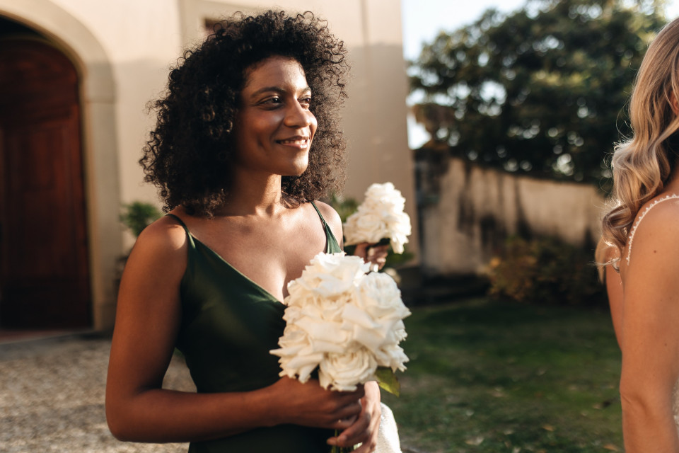 twee vrouwen in groene jurken die witte bloemen vasthouden