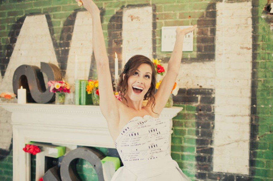 een bruid in een witte jurk houdt haar armen omhoog