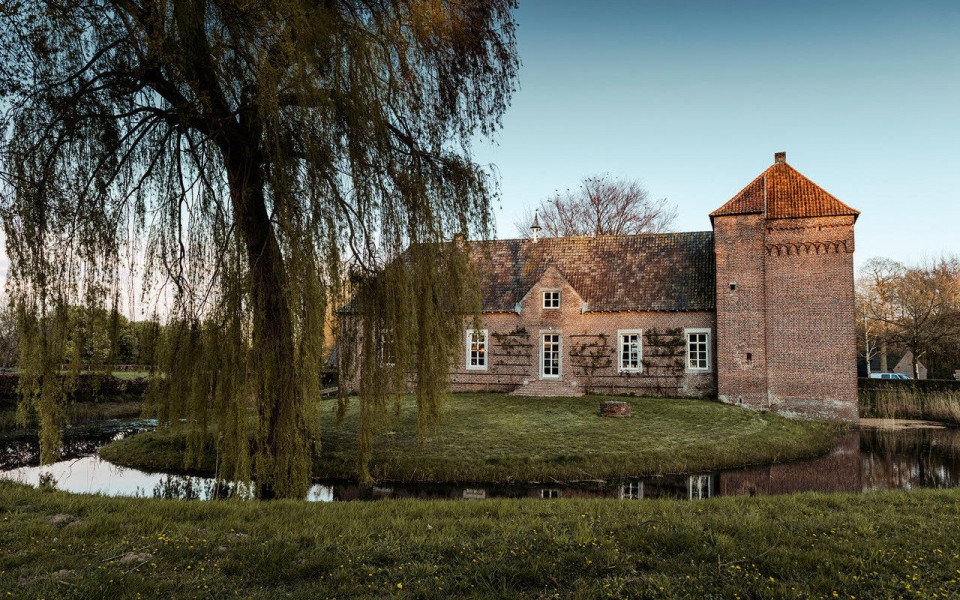 een groot bakstenen gebouw staat naast een vijver