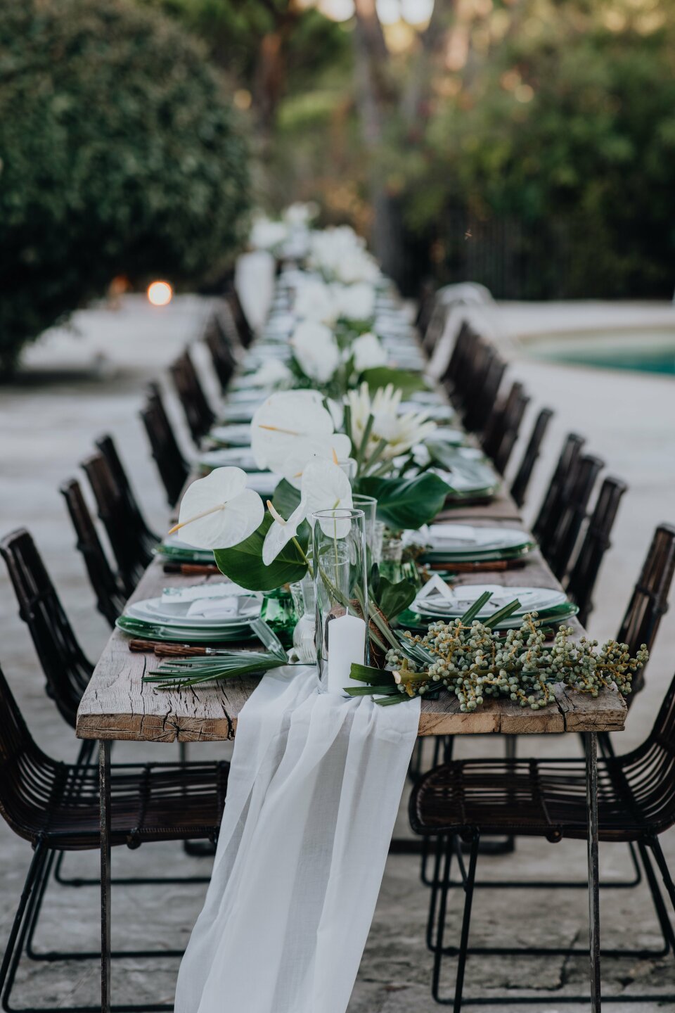 een lange tafel met witte bloemen en groen erop