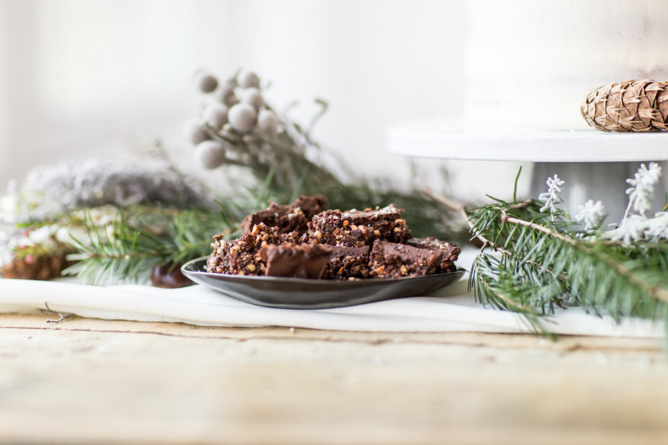 een bord met chocolade fudge op een tafel met groenblijvende takken