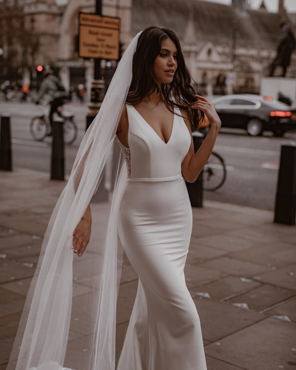 een bruid in een witte trouwjurk staat op straat