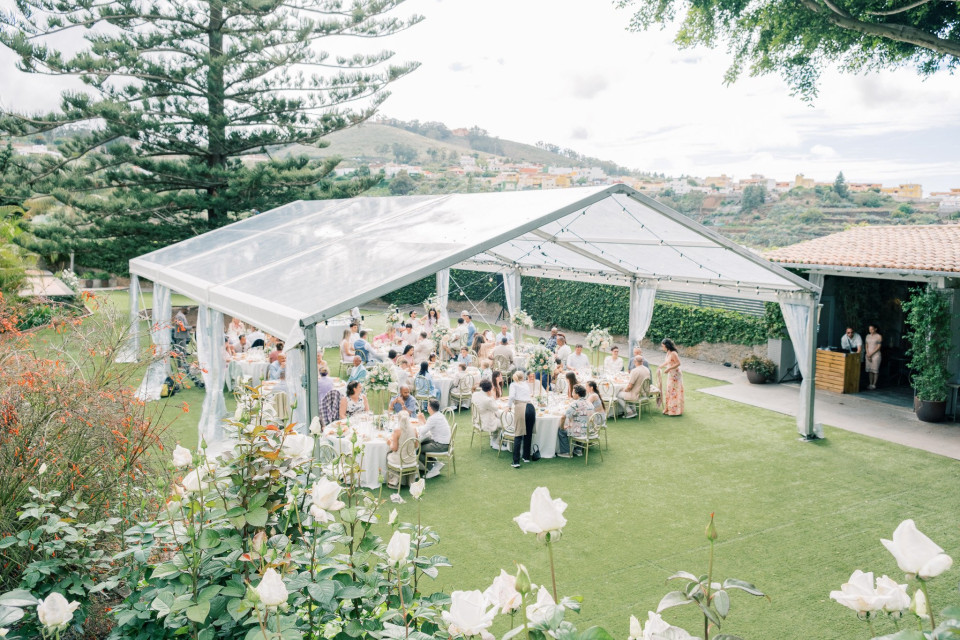 een trouwceremonie in een tuin met een witte tent