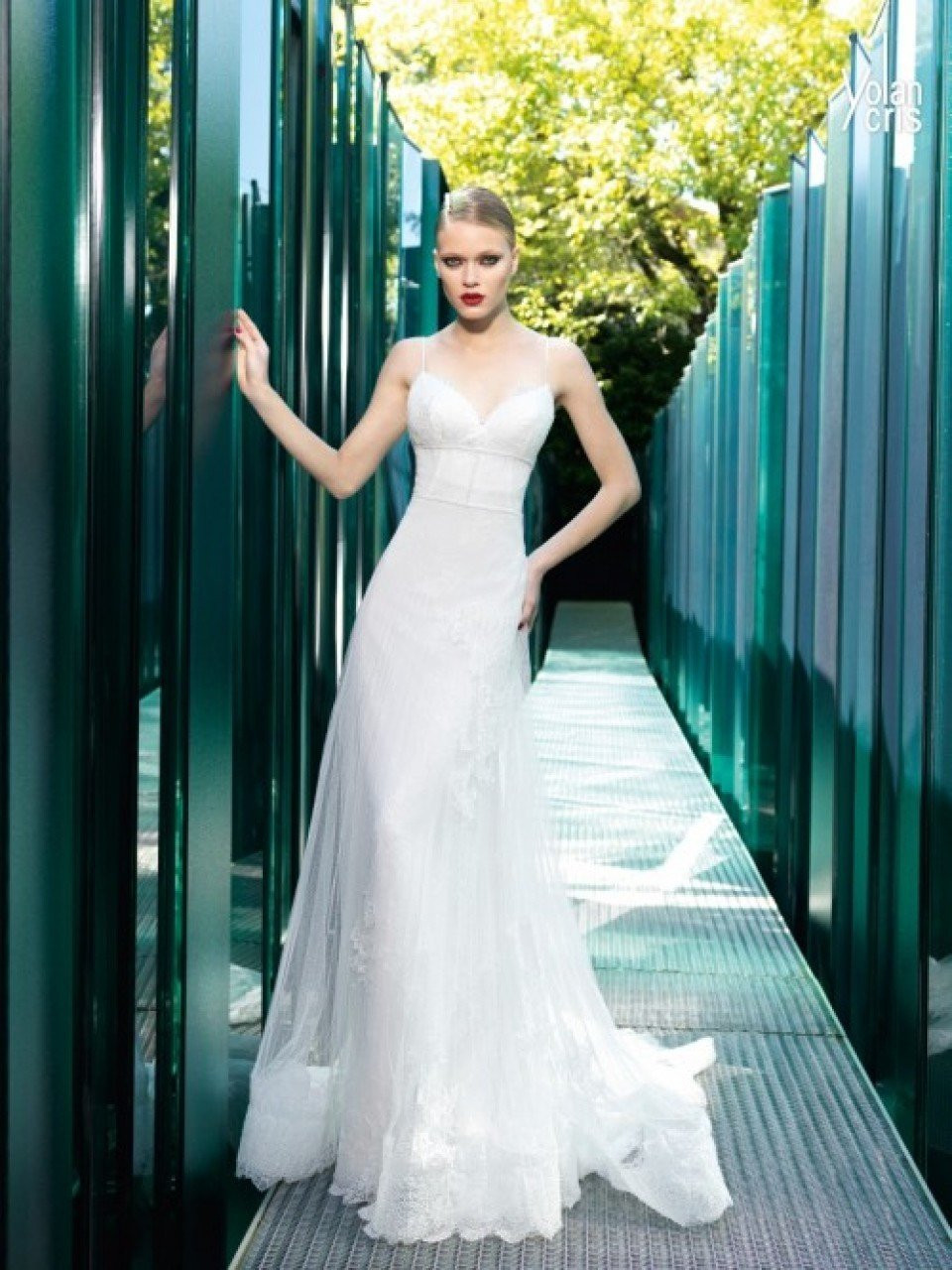 een mooie vrouw in een trouwjurk staat voor een glazen wand