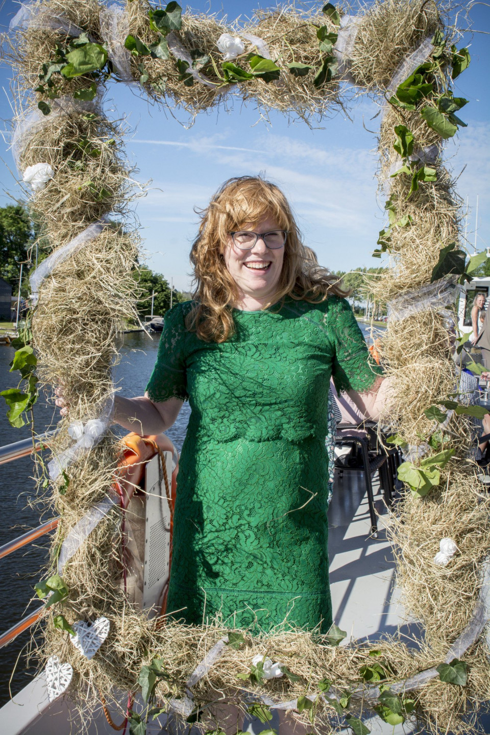 een vrouw in een groene jurk die een frame met hooi vasthoudt