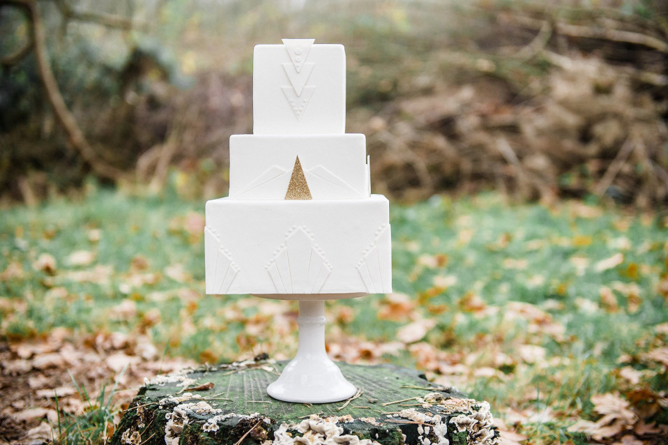 een witte bruidstaart op een houten standaard