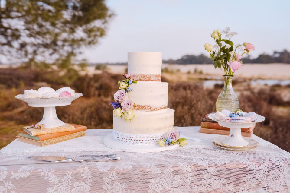 een bruidstaart op een tafel met boeken en vazen