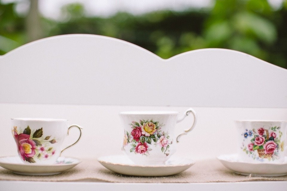 drie theekopjes en schotels op een bank