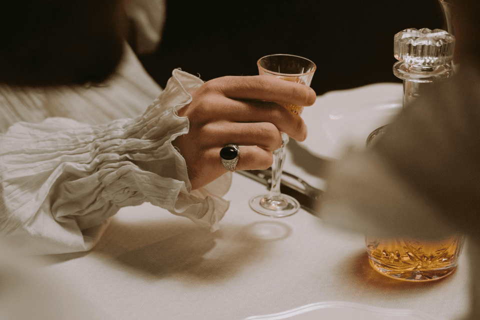 een persoon houdt een glas wijn aan een tafel