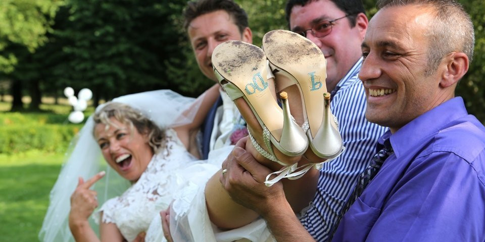 een man houdt de schoen van de bruid omhoog met zijn vrienden