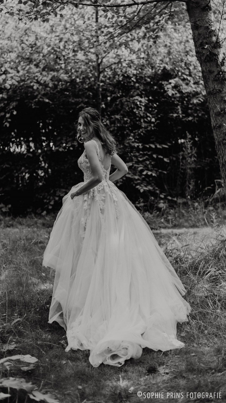 een bruid in een trouwjurk die door het bos loopt