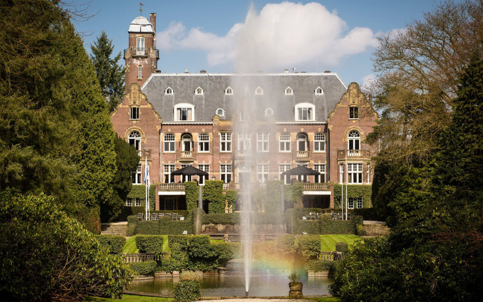 een groot gebouw met een fontein ervoor