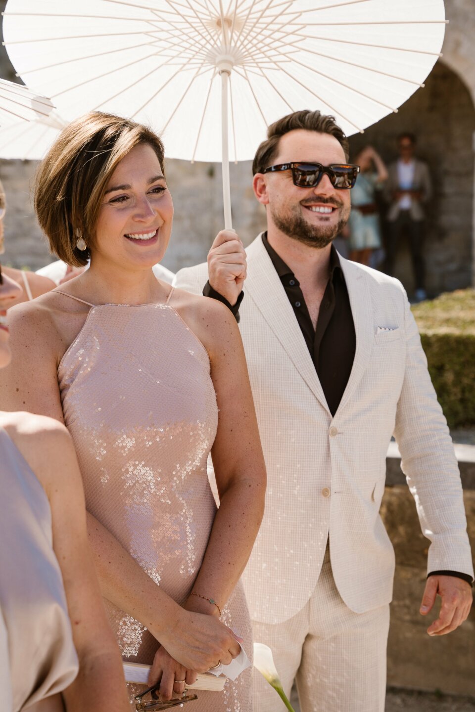 een man in een wit pak en een vrouw in een roze jurk met een paraplu