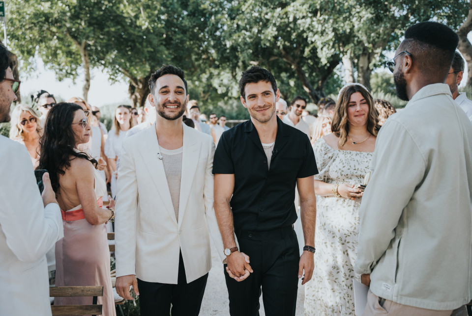 twee mannen lopen door het gangpad op een bruiloft