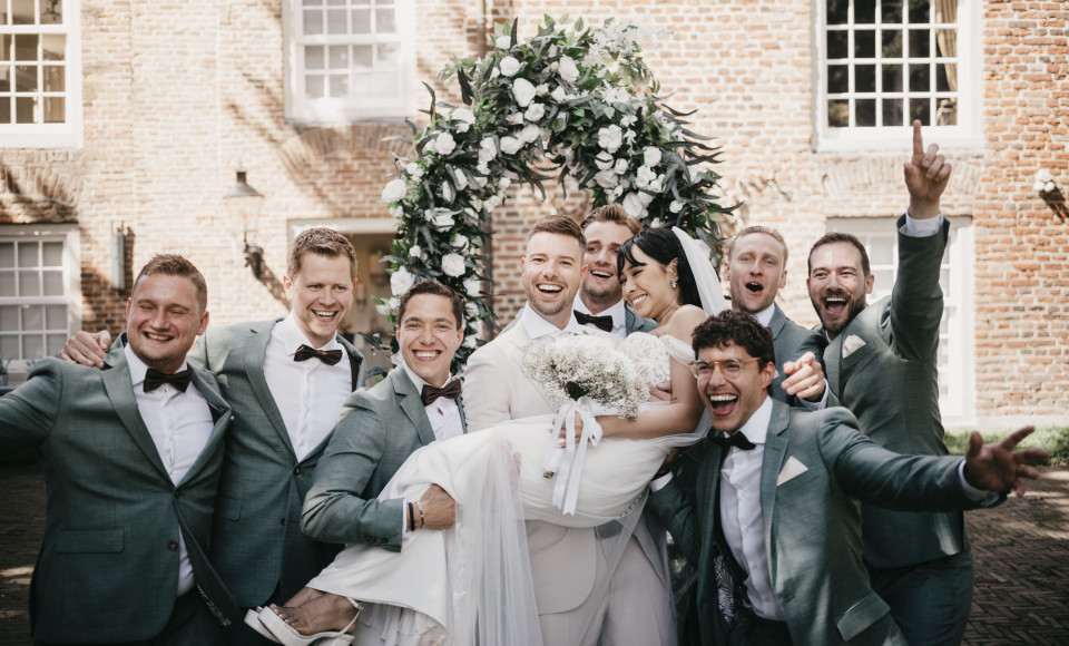 een groep bruidegommen en bruidsjonkers poseren voor een foto