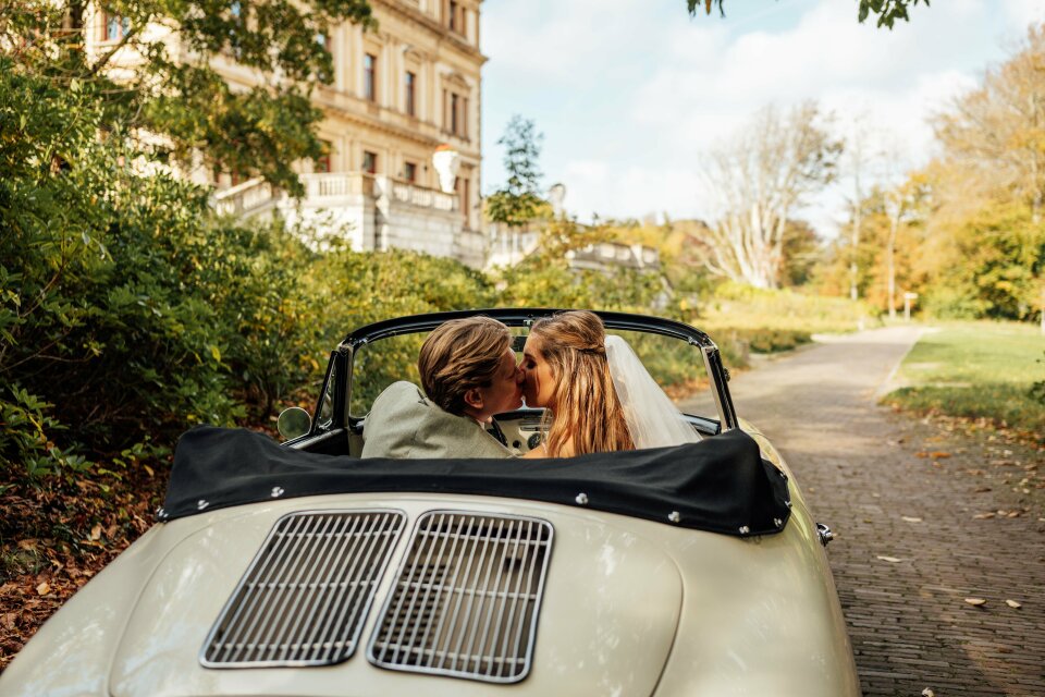 een bruid en bruidegom die in de achterkant van een auto kussen
