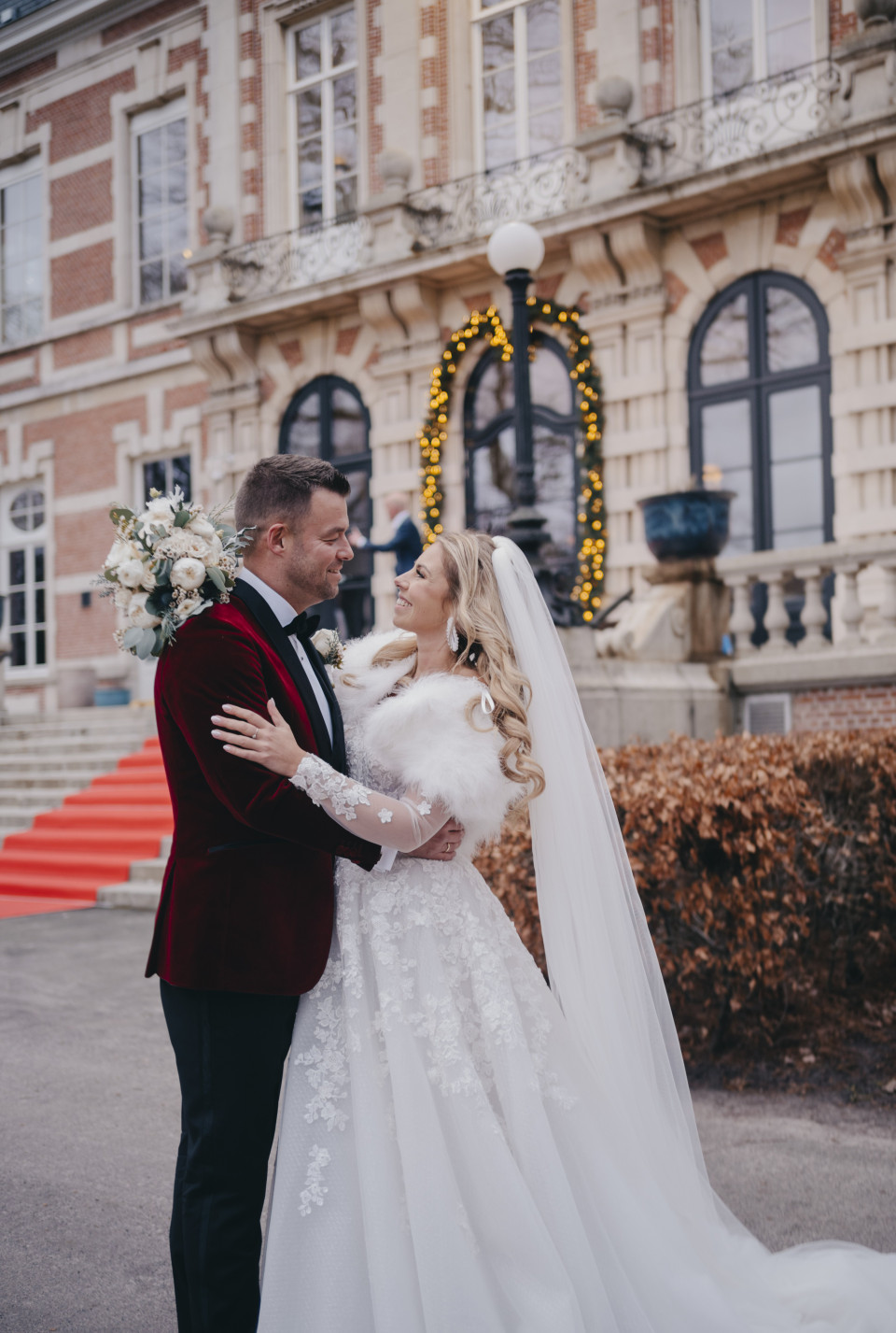 een bruid en bruidegom omhelzen voor een landhuis