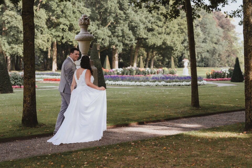 een bruid en bruidegom die poseren voor een foto in een park