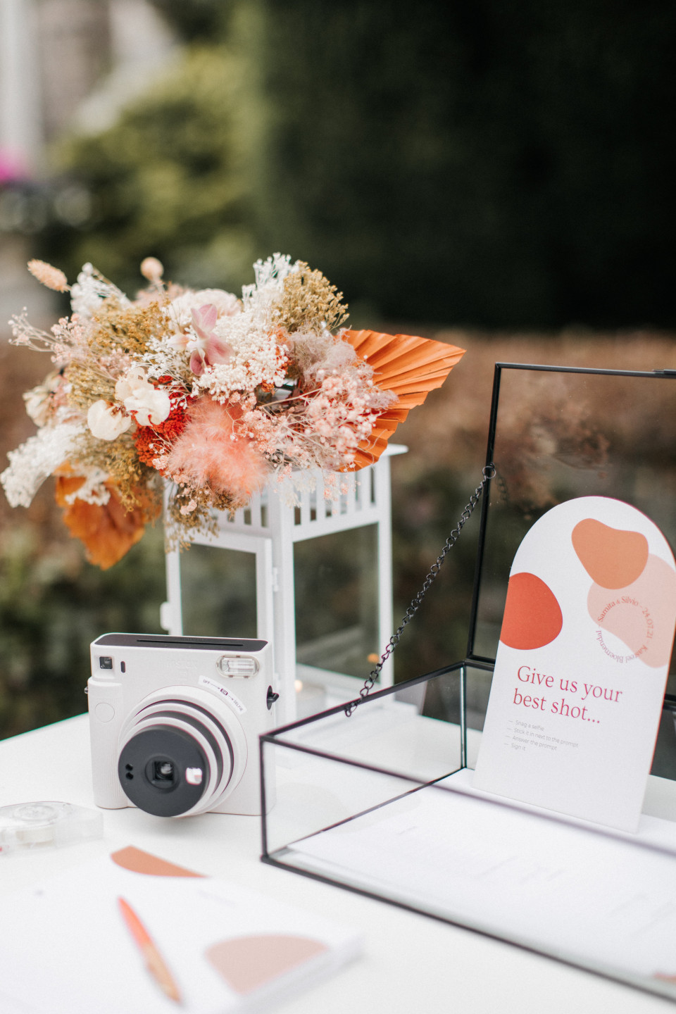 een oranje en wit boeket staat op tafel met een camera en een briefje