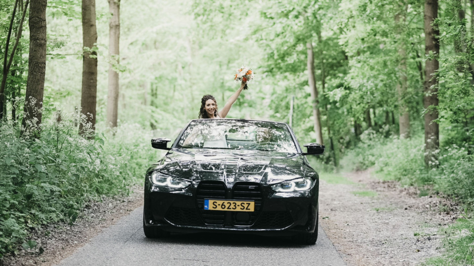 een vrouw rijdt in een auto op een weg in het bos