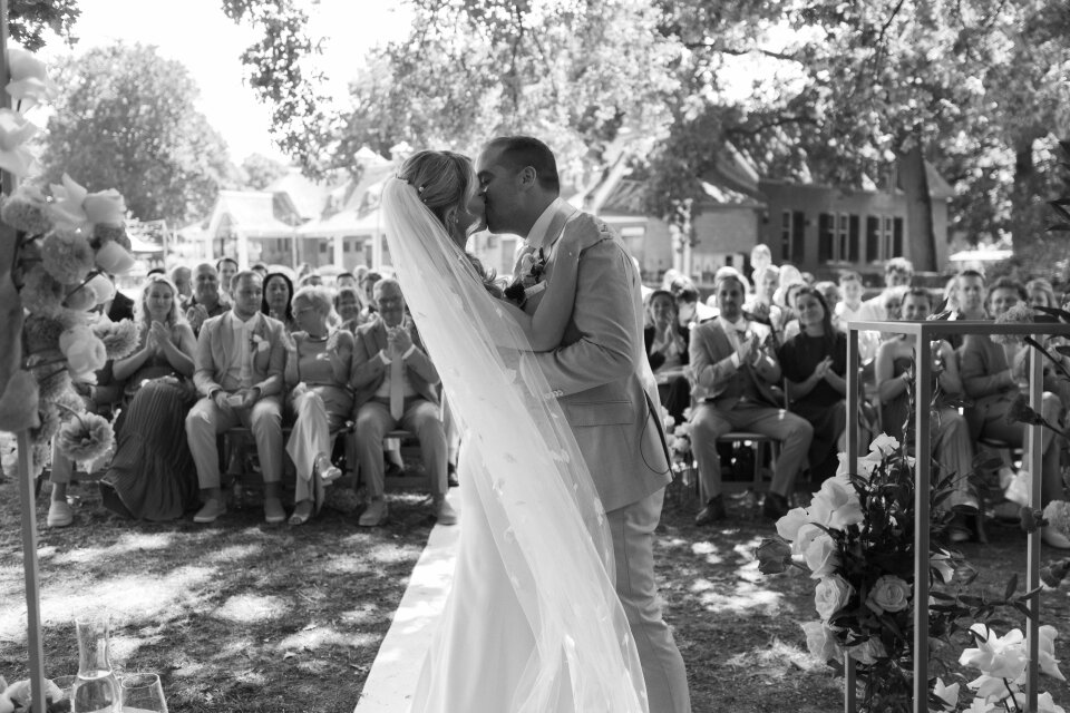 een zwart-wit foto van een bruid en bruidegom die kussen