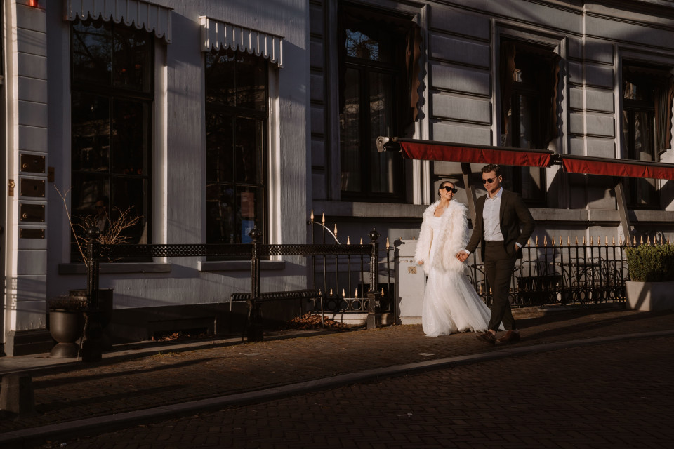 een bruid en bruidegom lopen door de straat voor een gebouw