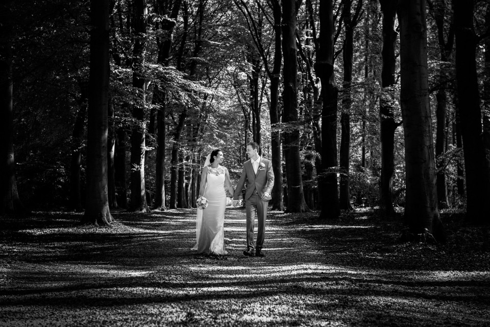een zwart-wit foto van een bruid en bruidegom in het bos