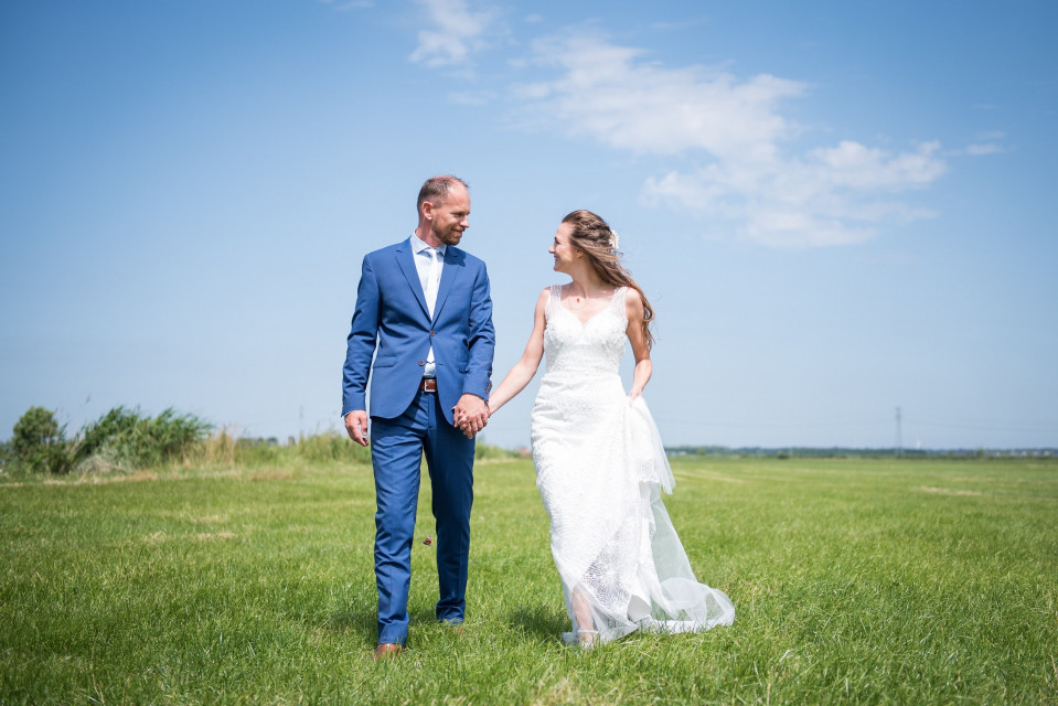 een bruid en bruidegom lopen in een veld