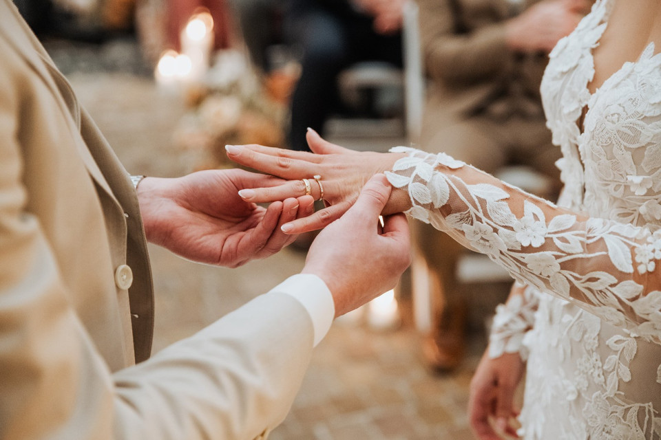 een man doet een trouwring om de vinger van een vrouw