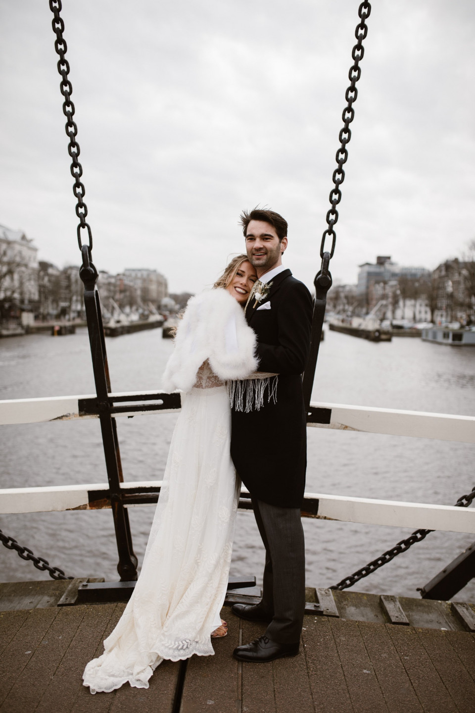 een bruid en bruidegom poseren voor een foto op een brug