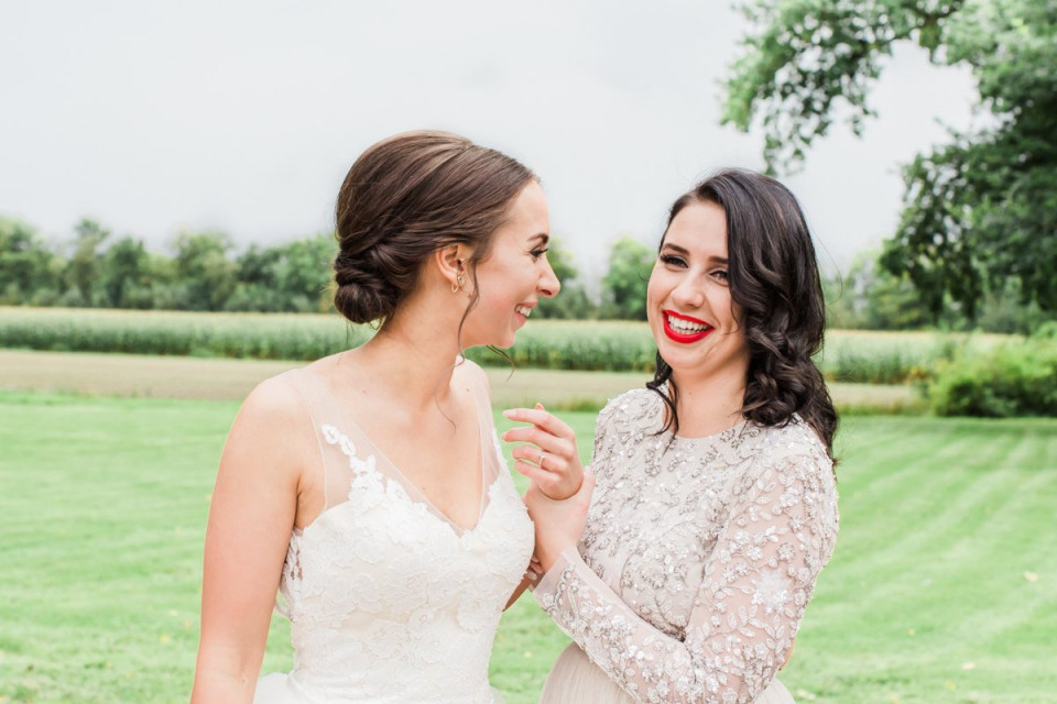 twee bruiden glimlachen naar elkaar in een veld