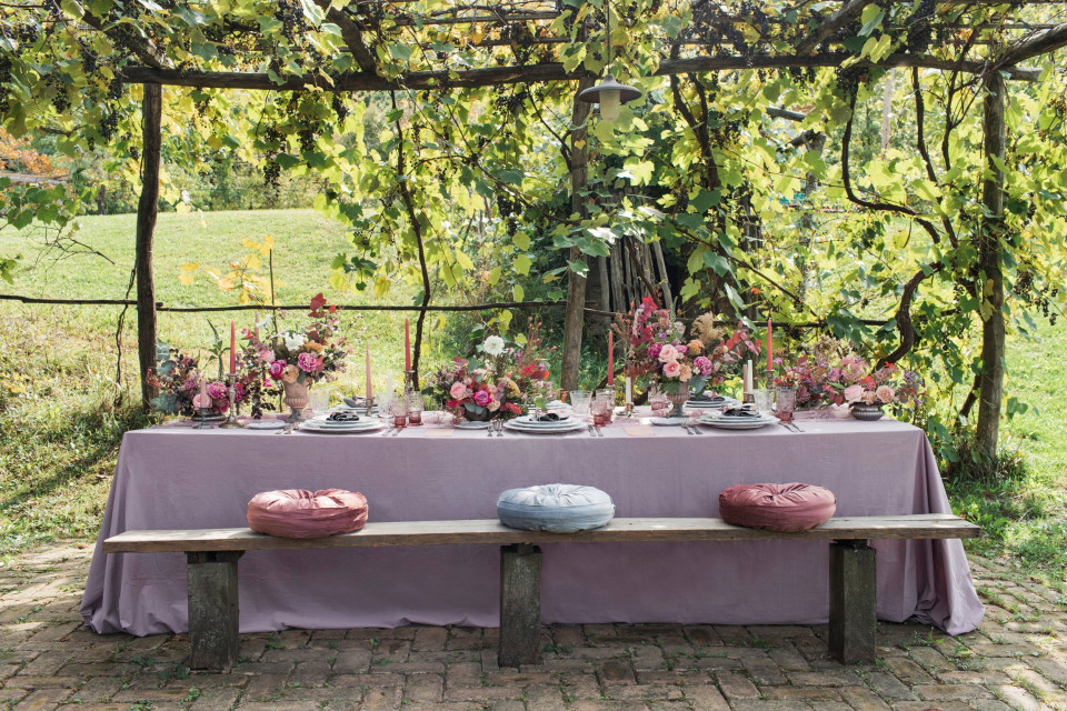 een tafel met paarse bloemen en bankjes onder een boom