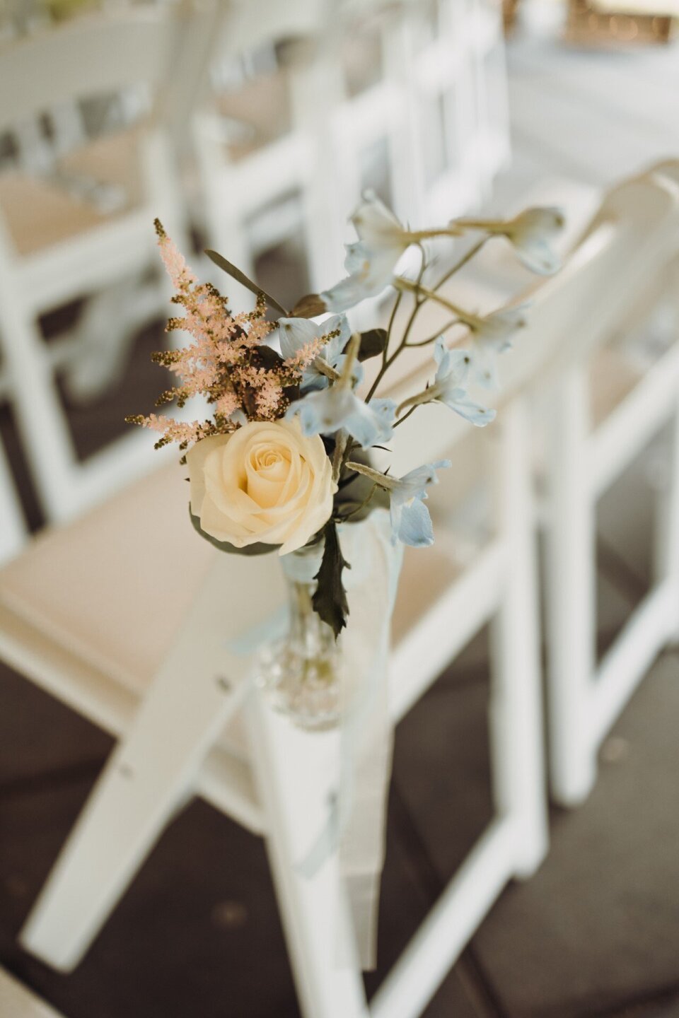 een arrangement van bloemen in een vaas op de achterkant van een stoel
